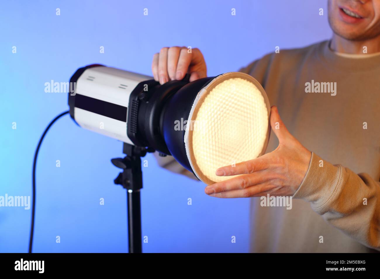 un flash con un modificatore acceso con un diffusore con una persona sullo sfondo Foto Stock un flash con un modificatore acceso con un diffusore con una persona sullo sfondo Foto Stock