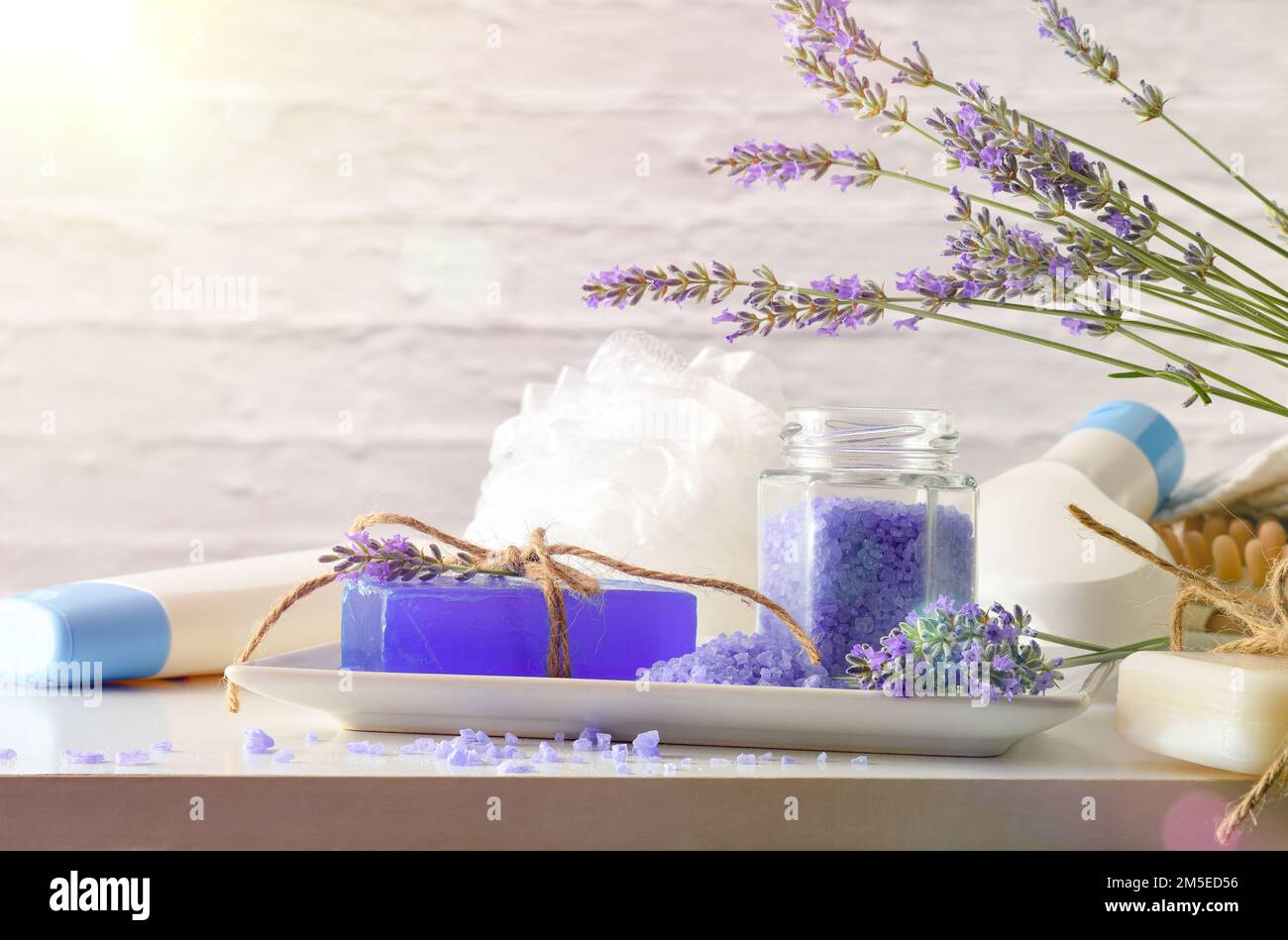 Prodotti da bagno con estratto di lavanda con elementi per l'igiene personale su tavolo bianco. Vista frontale. Composizione orizzontale. Foto Stock