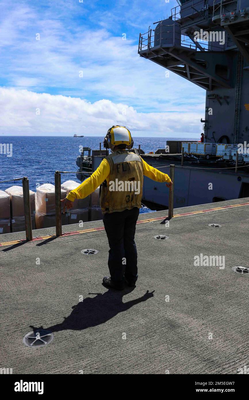 PHILIPPINE SEA (8 marzo 2022) Aviation Boatswain’s Mate (Handling) 2nd Class Princes Rosit, di Honolulu, segnala a un operatore di ascensori di abbassare un ascensore dal ponte di volo della portaerei di classe Nimitz USS Abraham Lincoln (CVN 72) Alla baia di hangar durante un rifornimento-a-mare con il comando militare di Sealift carico asciutto e la nave di munizioni USNS Alan Shepard (T-AKE 3). Abraham Lincoln Strike Group è in fase di implementazione pianificata nell'area delle operazioni della flotta USA 7th per migliorare l'interoperabilità attraverso alleanze e partnership, fungendo da forza di risposta pronta per l'uso Foto Stock