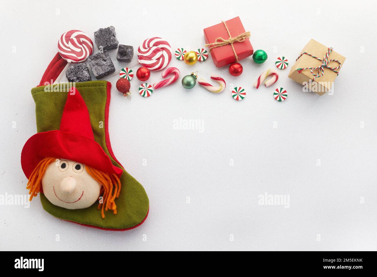 Calzino Befana con carbone dolce e caramella su fondo bianco. Tradizione italiana del giorno dell'Epifania. Foto Stock