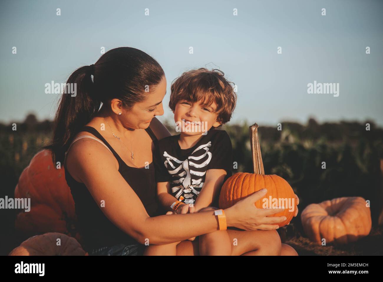 Una giovane mamma con suo figlio seduto su una balla hale in una zona di zucca a Bonita Springs, Florida Foto Stock