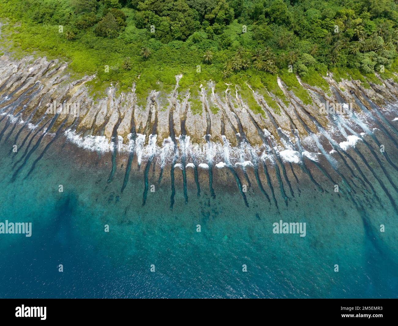 I canali di sperone e scanalatura hanno eroso sul bordo di un'isola remota nelle isole Salomone. Questo paese è sede di una spettacolare biodiversità marina. Foto Stock