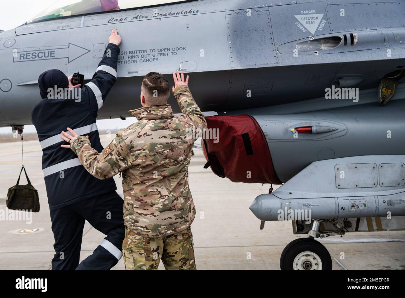STATI UNITI Mathew King, 480th Expeditionary Fighter Squadron pompiere, istruisce un pompiere rumeno sulle procedure per il salvataggio di un pilota da un F-16 Fighting Falcon Aircraft, 8 marzo 2022, presso la 86th Air base, Romania. 480th gli EFS Airmen lavorano fianco a fianco con le controparti rumene per familiarizzare e addestrare per le situazioni di emergenza. Foto Stock