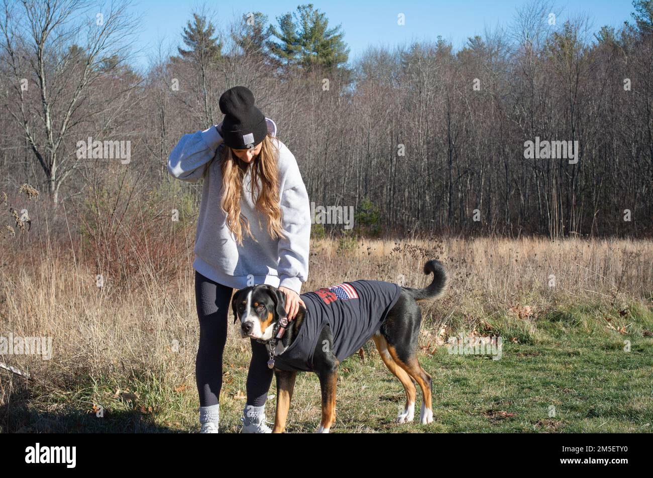 Ragazza con il suo cane di montagna svizzero che cammina fuori ai margini dei boschi nel New Hampshire USA Foto Stock