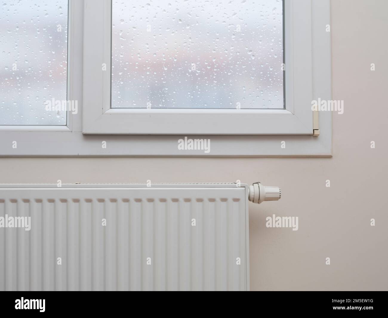 Un moderno radiatore bianco con un termostato sotto la finestra Foto Stock