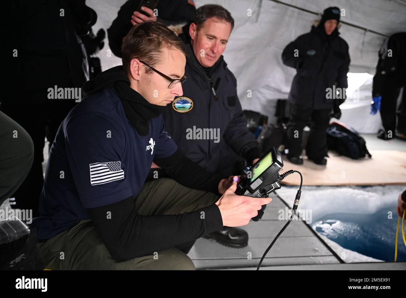 STATI UNITI NAVY ICE CAMP QUEENFISH (9 marzo 2022) – Electronic Technician (Navigation) 1st Classe Douglas Coffel, di Unmanned Undersea Vehicle Squadron (UVRON) 1-Keyport, Washington, a destra, mostra U.S. David A. Krumm, comandante degli Stati Uniti Il comando dell'Alaska del comando nord (ALCOM), la vista da una telecamera fissata a un veicolo sottomarino senza equipaggio (UUV) sotto il ghiaccio artico durante gli Stati Uniti Esercizio sul ghiaccio della Marina (ICEX) 2022. I test UUV hanno avuto luogo a Ice Camp Queenfish, un accampamento costruito su un galleggiante di ghiaccio 160 miglia nautiche al largo della costa dell'Alaska nell'Oceano Artico. Oltre al p Foto Stock