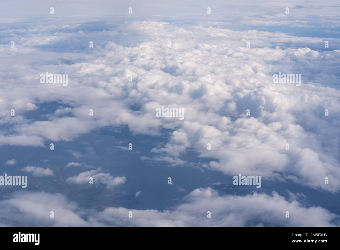 La vista dalla finestra piana alle nuvole e al suolo. Il paesaggio della superficie terrestre, visibile da un aeroplano sotto nuvole bianche e blu Foto Stock