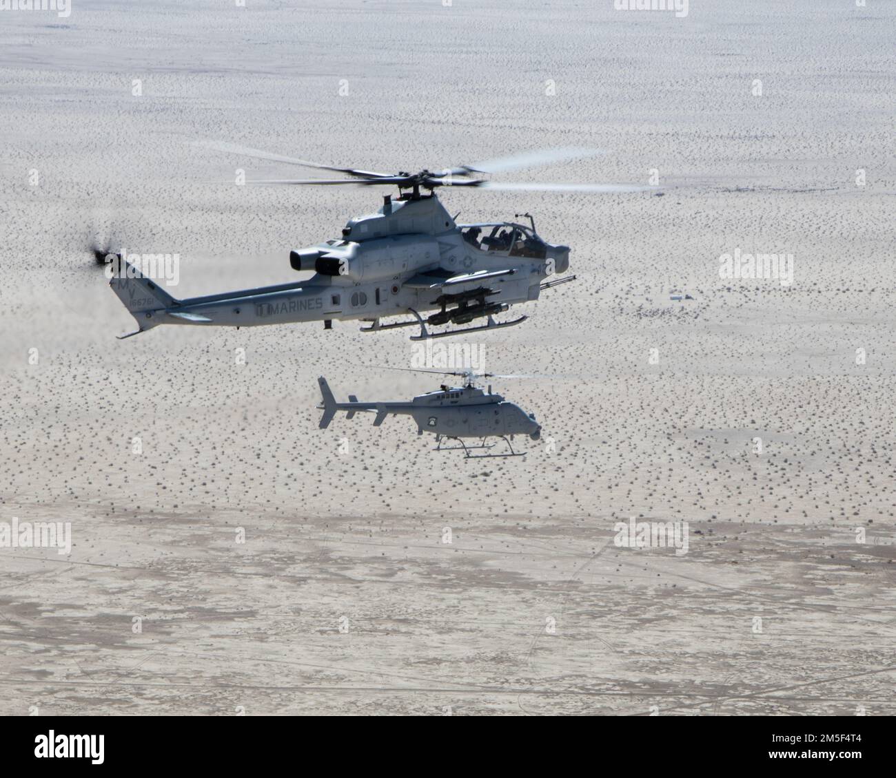 Un AH-1Z Viper (TOP) con Marine Operational and Test Evaluation Squadron 1 (VMX-1), e un MQ-8C Fire Scout elicottero senza equipaggio assegnato a Helicopter Sea Combat Squadron 23 (HSC-23), Conduct Strike Coordination and Reconnaisance Training nei pressi di El Centro, California, 10 marzo 2022. Lo scopo di questo esercizio era quello di consentire la familiarizzazione e lo sviluppo del concetto di teaming con-senza-presidiato. Foto Stock