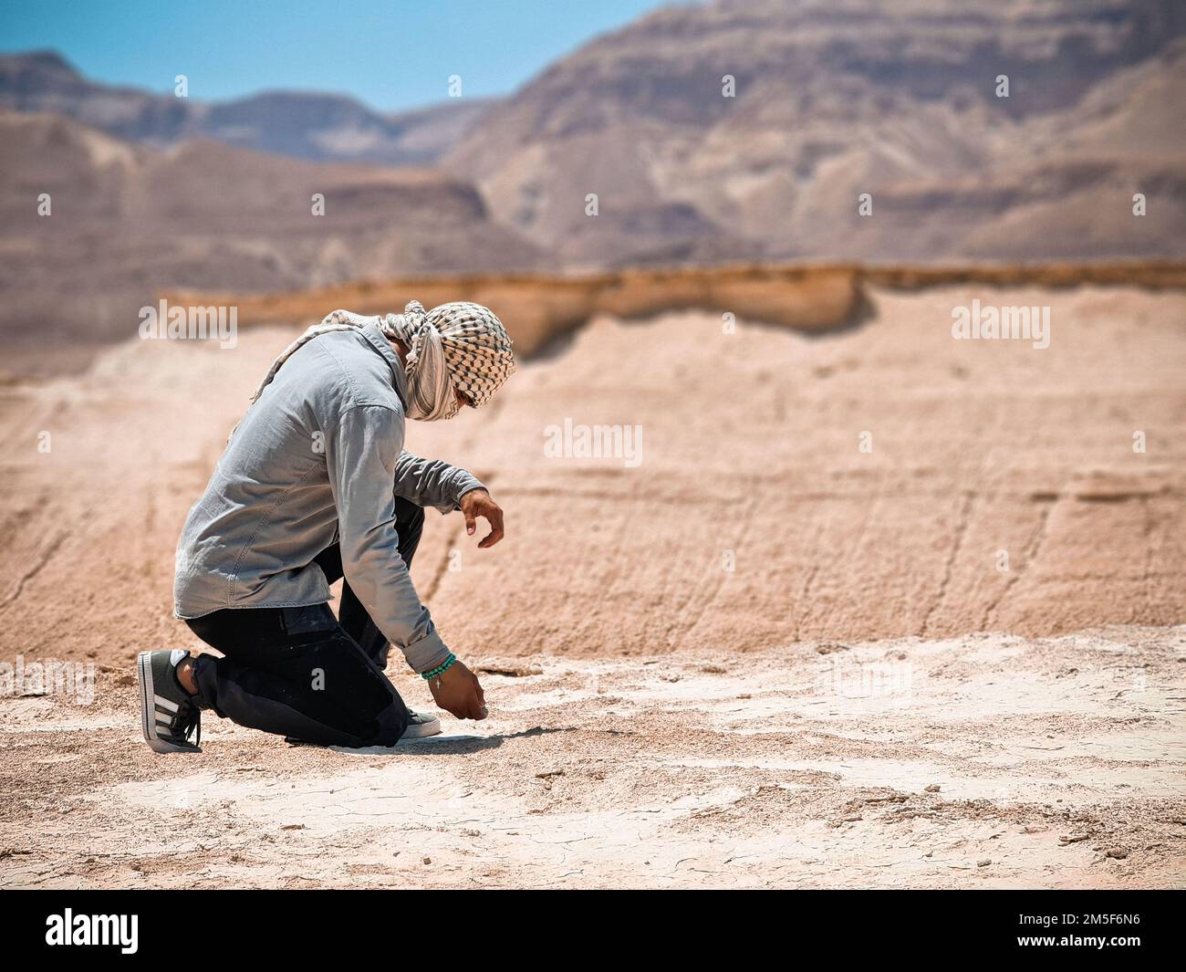 Uomo in ginocchio nel deserto Foto Stock