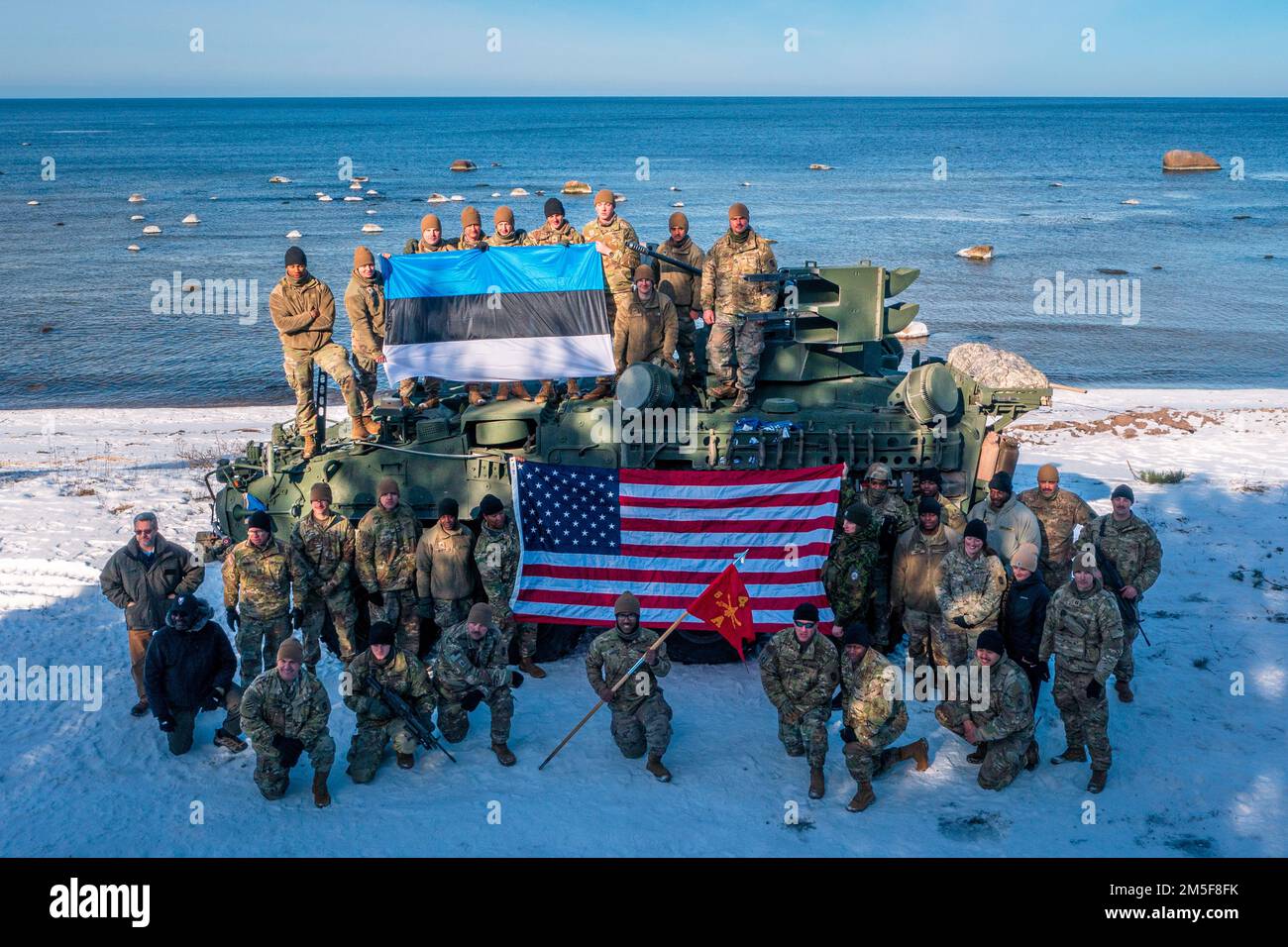 Estone e USA I soldati dell'esercito assegnati al comando di difesa dell'aeronautica & missilistica dell'esercito 10th, posano con gli Stati Uniti La nuova manovra dell'esercito Short Range Air Defense Stryker sotto le bandiere estoni e statunitensi dopo un evento di addestramento antincendio dal vivo di successo nel Golfo di Finlandia durante l'esercitazione Saber Strike 22 il 10 marzo 2022. L'esercizio si svolge fino a marzo con circa 13.000 partecipanti provenienti da 13 paesi ed è stato tenuto ogni 2 anni dal 2010. L'evento di formazione è programmato durante l'inverno per dimostrare la capacità di operare in condizioni austere. Durante lo Sciopero Saber, il battaglione del 5th, 4th Foto Stock