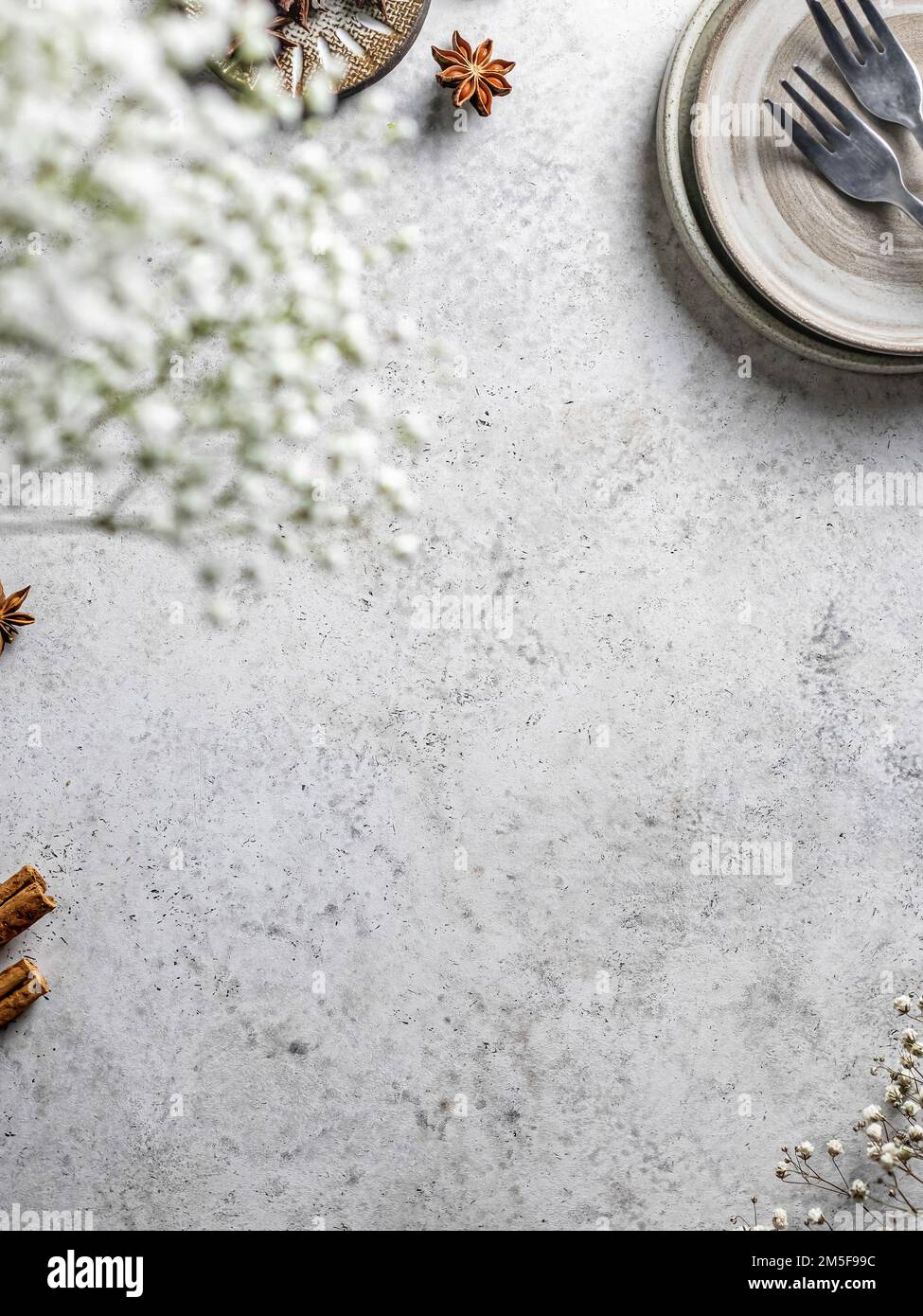 Tavolo con fiori primaverili, posate e piatti da dessert e cannella. Posiziona per testo, spazio di copia, disposizione piatta. Vista dall'alto. Orientamento verticale Foto Stock