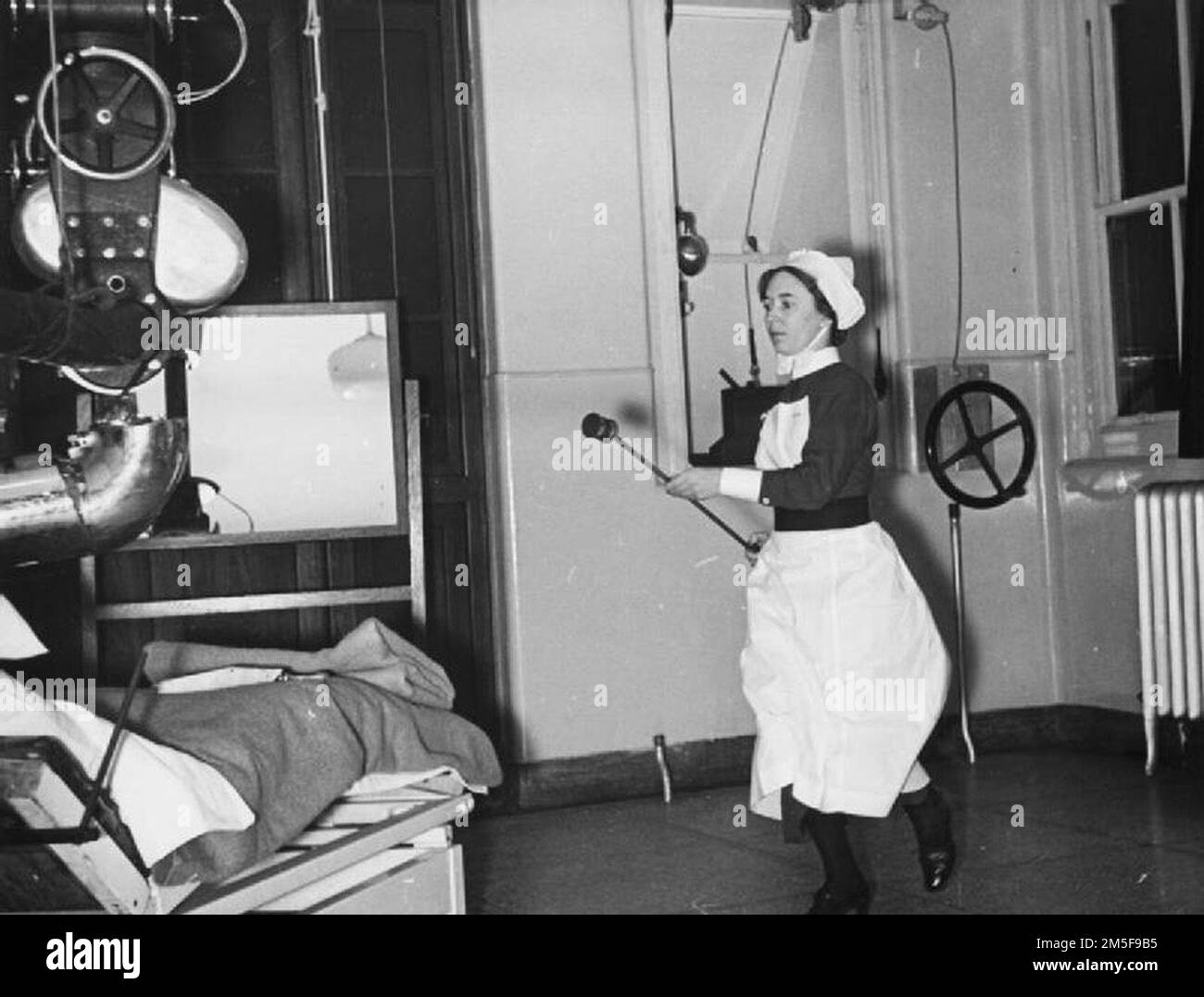 Un'infermiera precipita le radiazioni attraverso la stanza verso l'apparecchio per il trattamento del cancro in un ospedale di Londra nel 1940. Il radio è alloggiato in un apposito contenitore all'estremità di un'asta lunga. Foto Stock