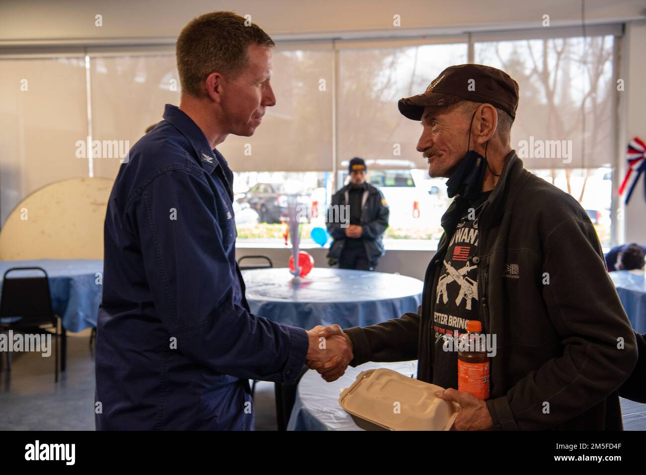 Il capitano Jason Smith, comandante del settore della Guardia Costiera Houston-Galveston, scuote le mani con un veterano dopo aver pranzato con lui durante un evento di volontariato della Combined Federal Campaign nella casa di un veterano di Houston a Houston, Texas, il 11 marzo 2022. I membri hanno cucinato e tagliato il pranzo ai residenti locali accanto agli Stati Uniti L'immigrazione e l'applicazione delle dogane e il Michael E. DeBakey Veterans Affairs Medical Center, come parte di un evento volontario in collaborazione con gli Stati Uniti Vets Houston e la Veteran Initiative. Foto Stock