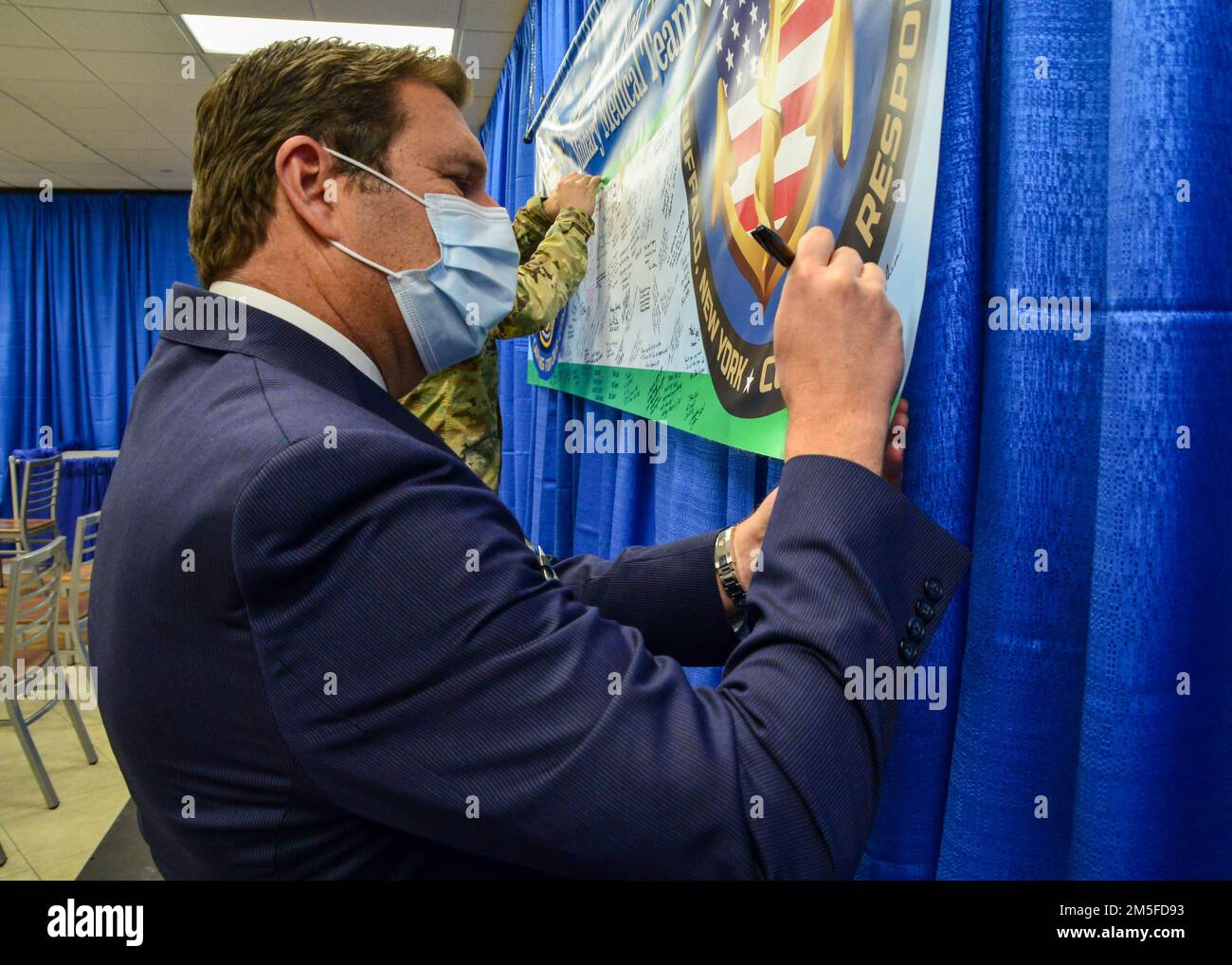 220311-N-RB168-0232 BUFFALO, NY. (11 marzo 2022) – Thomas Quatroche, presidente di Erie County Medical Center Corporation (ECMCC), firma un banner di ringraziamento alla conferenza stampa di fine missione del Dipartimento della Difesa (DoD) Military Medical Team (MMT) presso l'Erie County Medical Center (ECMC). Questo MMT, tutti i membri attivi degli Stati Uniti Navy, è stata la prima ad essere schierata dal DoD a sostegno degli ospedali civili durante la pandemia COVID-19 per fornire supporto clinico agli operatori sanitari di prima linea. Il loro supporto è stato principalmente centrato nelle unità di pronto soccorso e terapia intensiva dell'ECMC. BUFF Foto Stock
