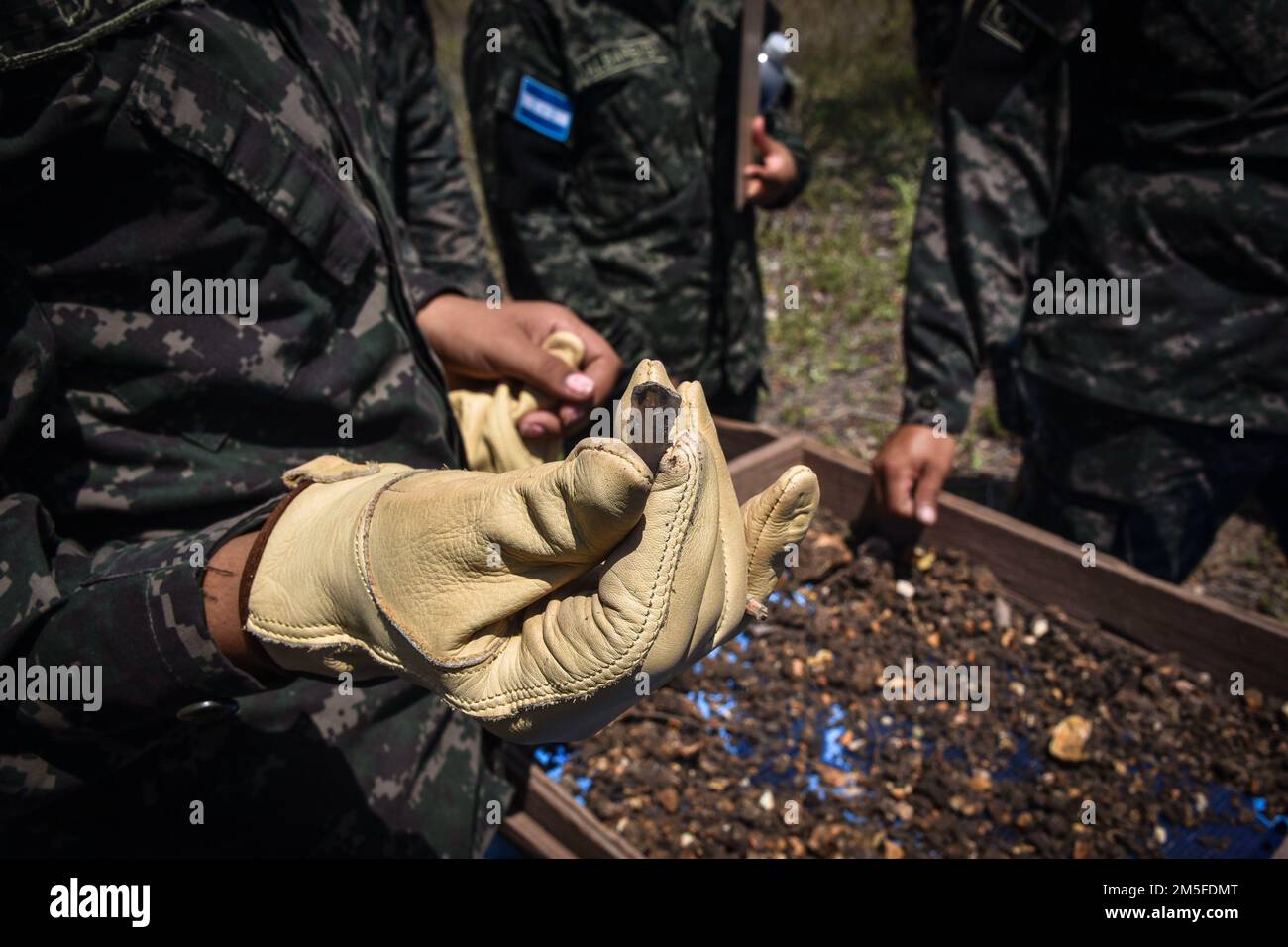 Un soldato Honduran con la Brigata della Fanteria del 120th mostra un pezzo di ossidiana trovato durante un'indagine sui pit di test a Las Mesas, Copan, Honduras, 11 marzo 2022. La Task Force-Bravo e il comando per gli affari civili e le operazioni psicologiche hanno collaborato con l'esercito e l'Istituto di Antropologia dell'Honduran per valutare i siti del patrimonio culturale colpiti dalle catastrofi naturali a Copan, Honduras, dal 7 al 11 marzo. Foto Stock