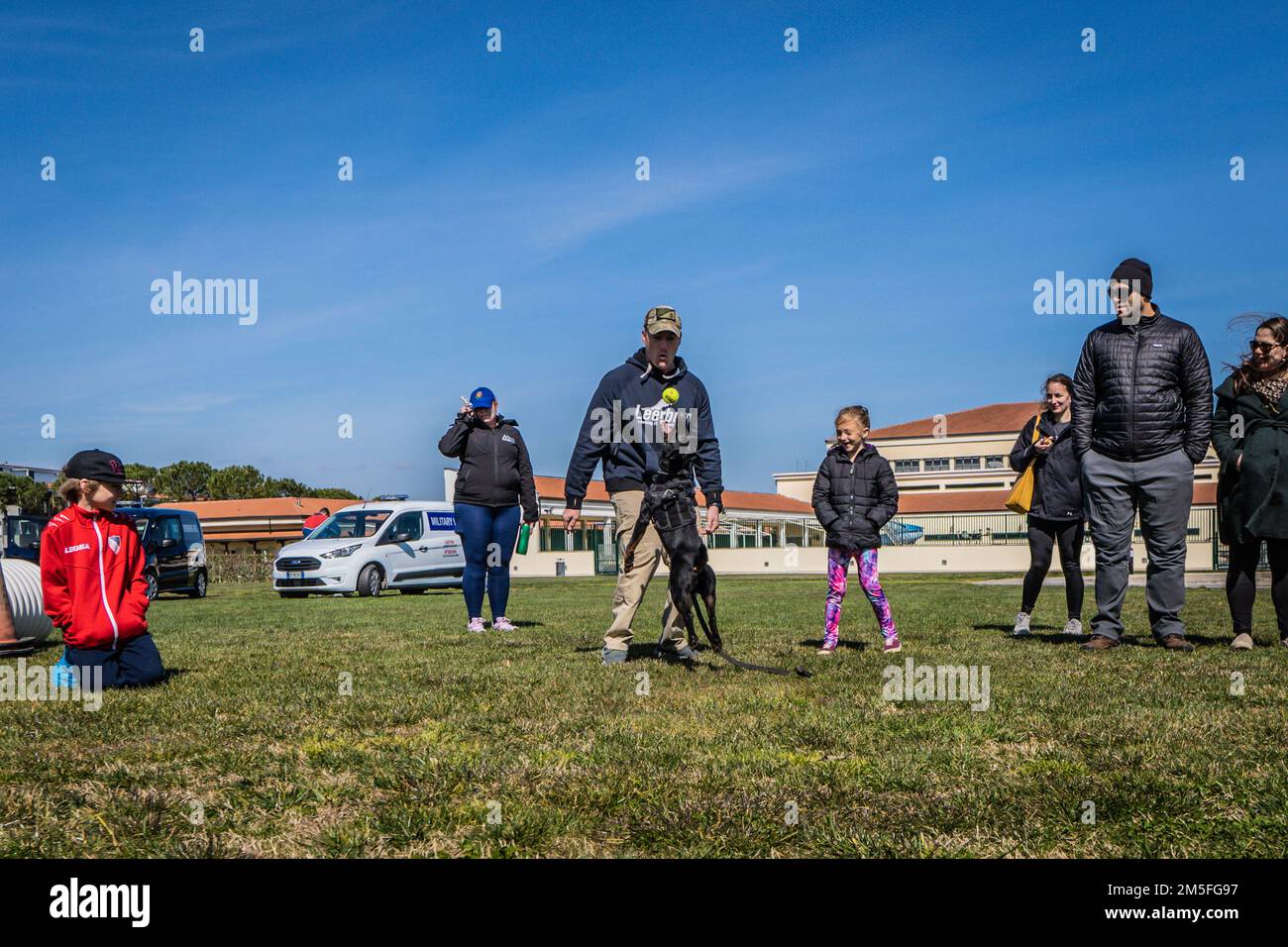 STATI UNITI Scott Chilko, capo del Master-at-Arms della Marina, al centro, lancia una palla per Military Working Dog (MWD) Boy durante una dimostrazione di abilità a bordo Naval Support Activity (NSA) Napoli Support Site a Gricignano, Italia, 12 marzo 2022. La dimostrazione di abilità fa parte della celebrazione della Giornata dei Veterani K-9 della NSA Naples MWD Security Team, organizzata per commemorare il servizio e i sacrifici dei cani militari e da lavoro americani e per educare i membri della comunità NSA Naples al programma MWD. La NSA Naples è una base operativa a terra che consente alle forze nazionali statunitensi, alleate e partner di essere dove si trovano Foto Stock