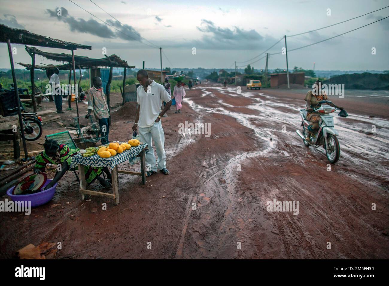 Ragazza che vende mango vicino alla strada sterrata in sikasso, Mali, Africa occidentale Foto Stock