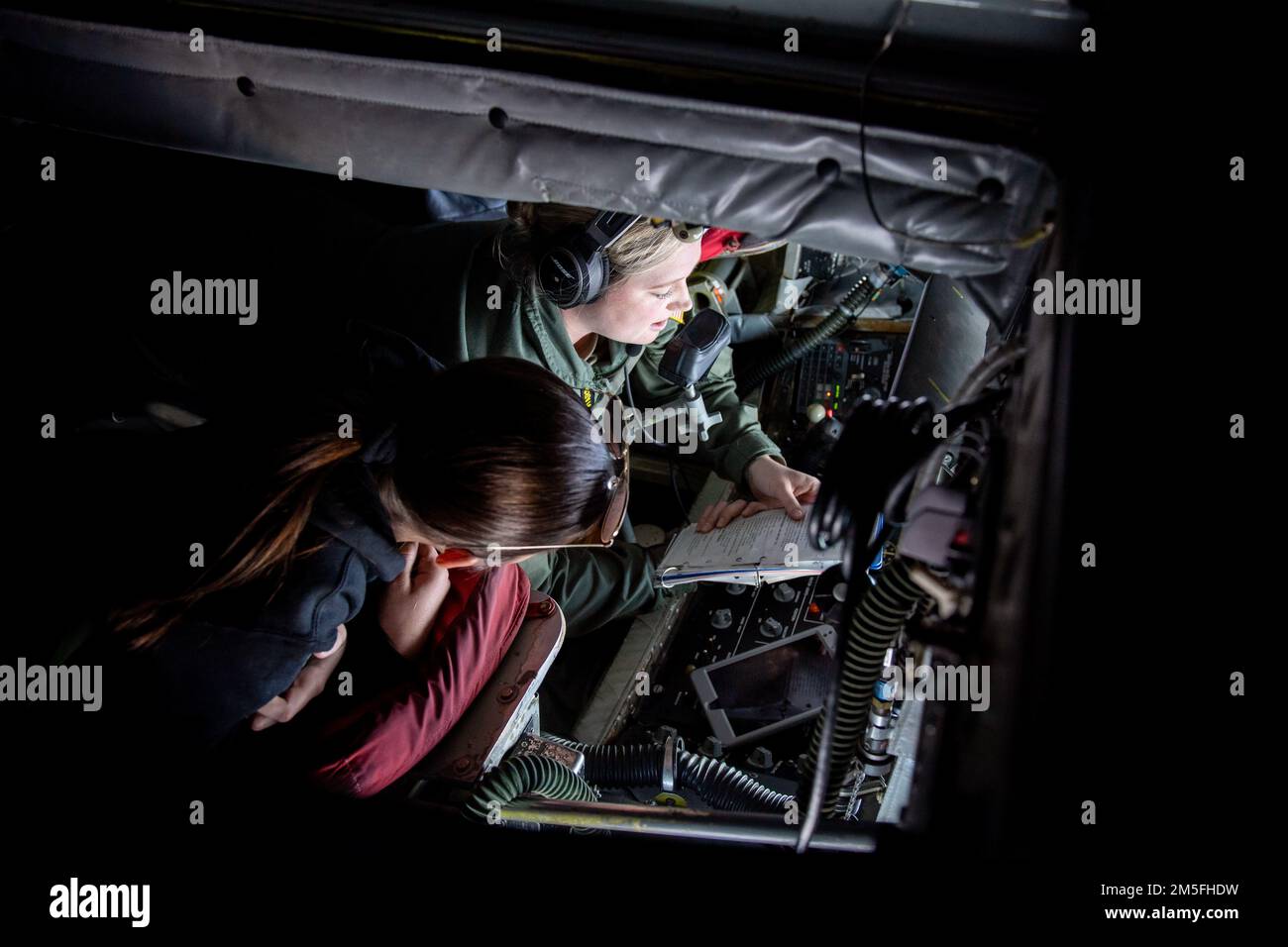 STATI UNITI Air Force Airman 1st Class Cassandra Wesley, un operatore di boom assegnato al 91st Air Refuelling Squadron, esamina una lista di controllo con Evelynn Kite, un cadetto ROTC della Florida state University, prima di una missione di rifornimento sul sud-est degli Stati Uniti, 12 marzo 2022. Gli operatori del braccio hanno la capacità di pompare migliaia di libbre di combustibile a qualsiasi aeromobile capace, a migliaia di piedi dal suolo, consentendo una rapida mobilità globale. Foto Stock