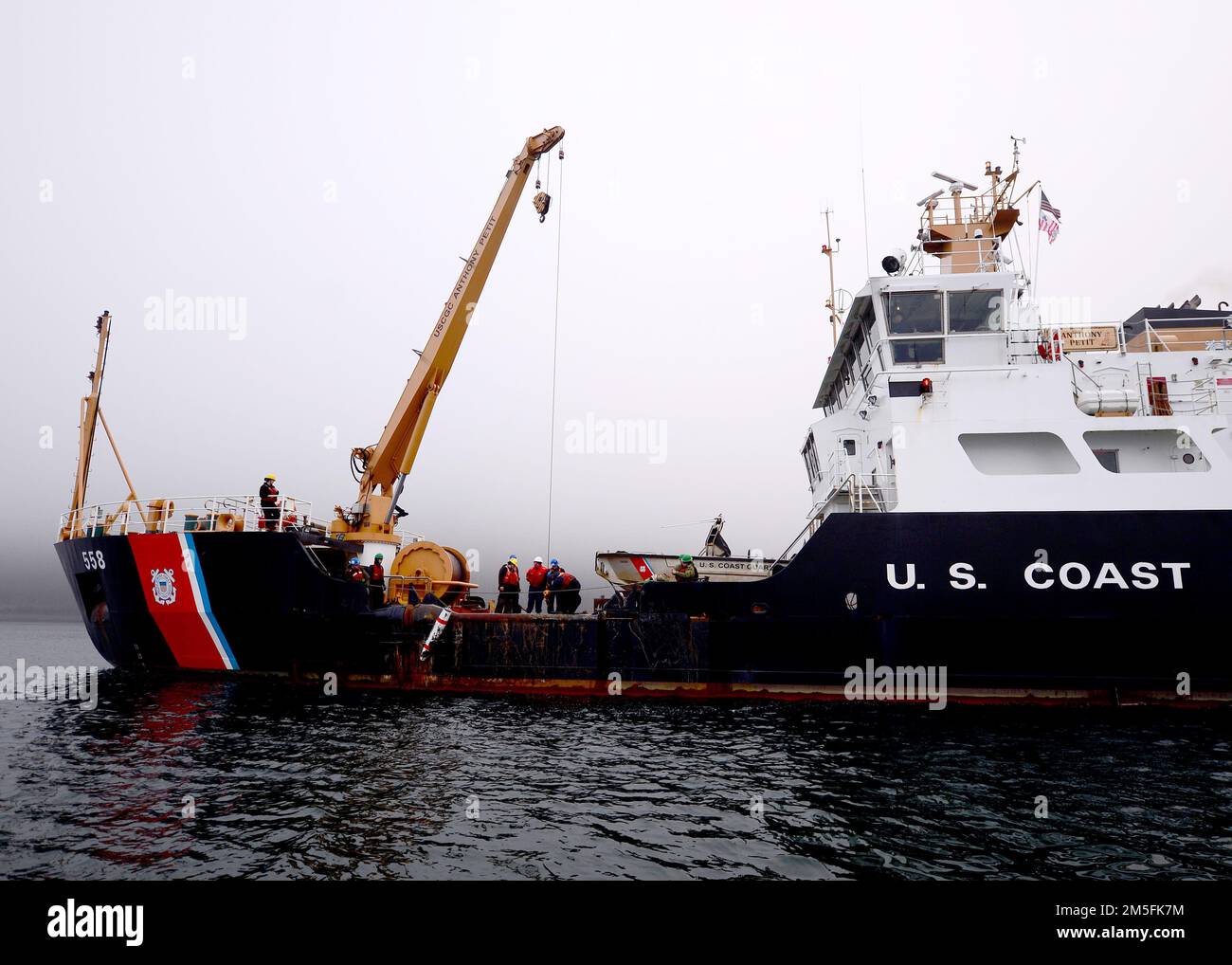 STATI UNITI Gli operatori del settore Coast Guardsmen utilizzano una gru a braccio per sollevare un supporto di addestramento inerte situato negli Stati Uniti Navy Explosive Ordnance Disposal Mobile Unit (EODMU) 1 a bordo della gara di boa costiera di classe Keeper USCGC Anthony Petit (WLM 558) nel canale di Gastineau vicino a Juneau, Alaska, 13 marzo 2022, durante l'esercizio ARCTICE EDGE 2022 (AE22). AE22 è un esercizio difensivo per gli Stati Uniti Northern Command e forze armate canadesi per dimostrare ed esercitare la nostra capacità di dispiegarsi e operare rapidamente nell'Artico. Foto Stock