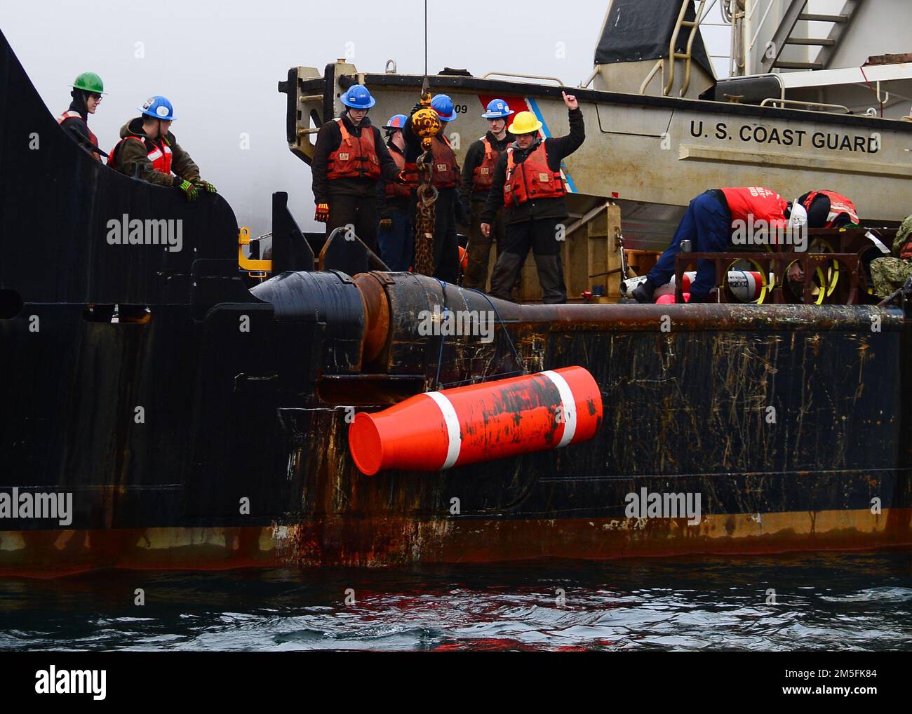 STATI UNITI Gli operatori del settore Coast Guardsmen utilizzano una gru a braccio per sollevare un supporto di addestramento inerte situato negli Stati Uniti Navy Explosive Ordnance Disposal Mobile Unit (EODMU) 1 a bordo della gara di boa costiera di classe Keeper USCGC Anthony Petit (WLM 558) nel canale di Gastineau vicino a Juneau, Alaska, 13 marzo 2022, durante l'esercizio ARCTICE EDGE 2022 (AE22). AE22 è un esercizio difensivo per gli Stati Uniti Northern Command e forze armate canadesi per dimostrare ed esercitare la nostra capacità di dispiegarsi e operare rapidamente nell'Artico. Foto Stock