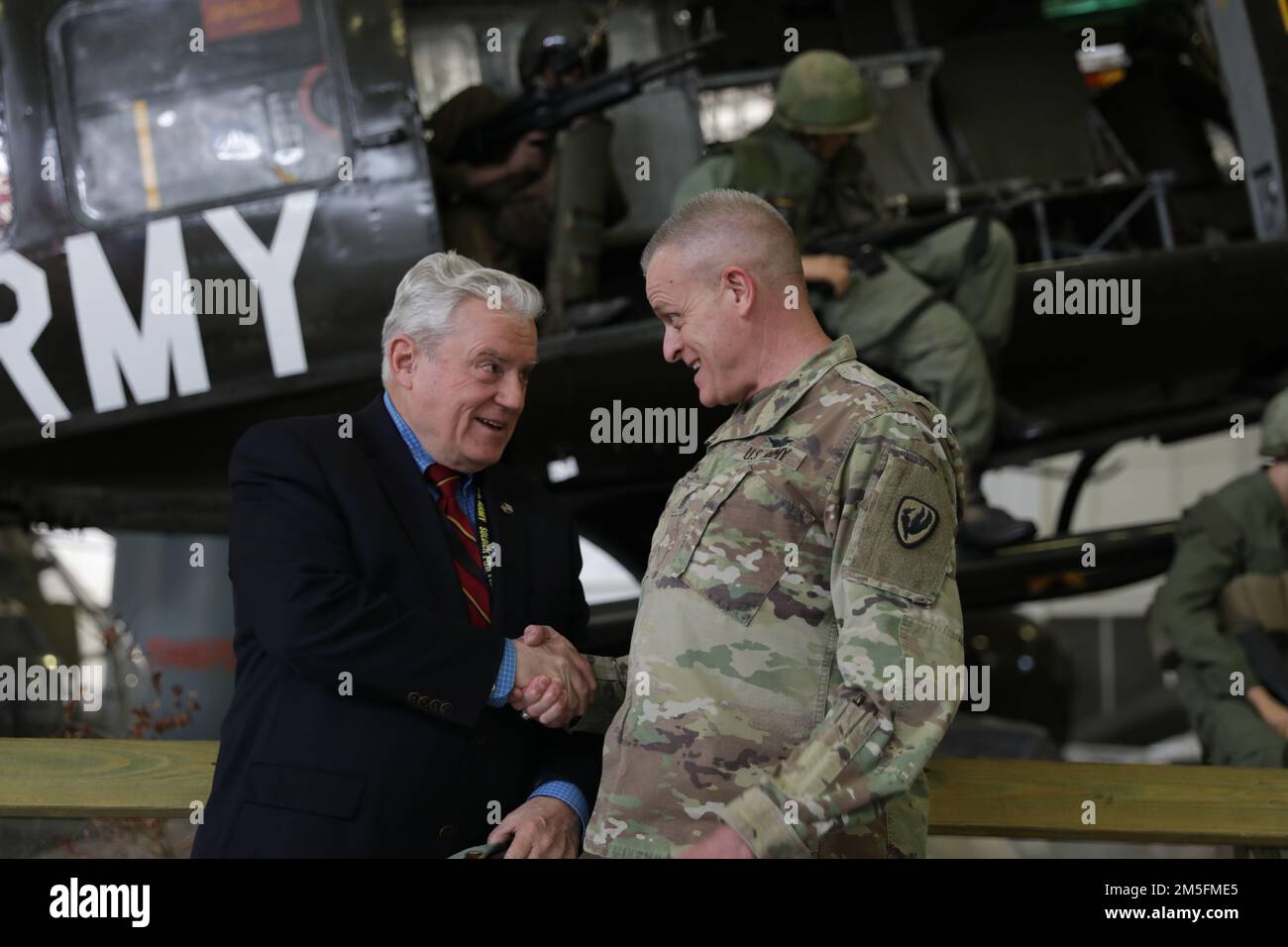 Thomas Green e il comando Sgt. Maj. Charles Hancock scuotono le mani davanti a un Bell UH-1 Iroquois display statico presso gli Stati Uniti Army Aviation Museum, Fort Rucker, Alabama, 14 marzo 2022. Foto Stock