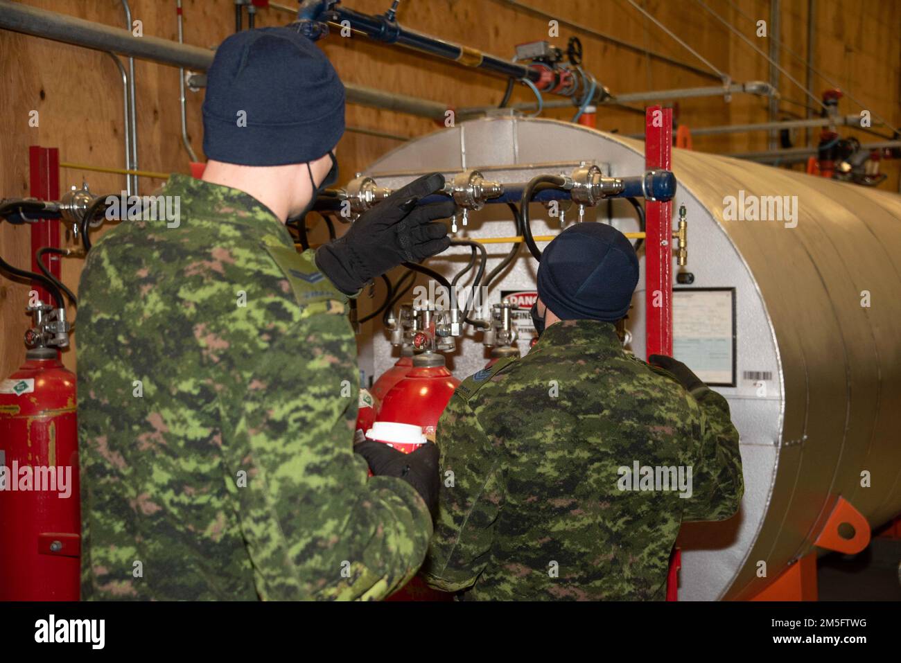 Royal Canadian Air Force Fire Fighter, il sergente Jeff Hawley spiega come funzionano gli allarmi e i sensori di calore nell'hangar per l'equipaggio addetto alla manutenzione, il 15 marzo 2022, presso la Forward Operating Location di Yellowknife, territori nordoccidentali. NORAD Operation NOBLE DEFENDER 22-2 è un'operazione di difesa aerea che si svolge dal 14 al 17 marzo 2022 e che coinvolge una serie di aerei militari della Royal Canadian Air Force (RCAF) e dell'aviazione militare degli Stati Uniti. Il personale e gli aerei sono basati fuori dalla stazione di allarme delle forze canadesi, Nunavut; Whitehorse, Yukon; Yellowknife, Territori nordoccidentali; e 5 Wing Foto Stock