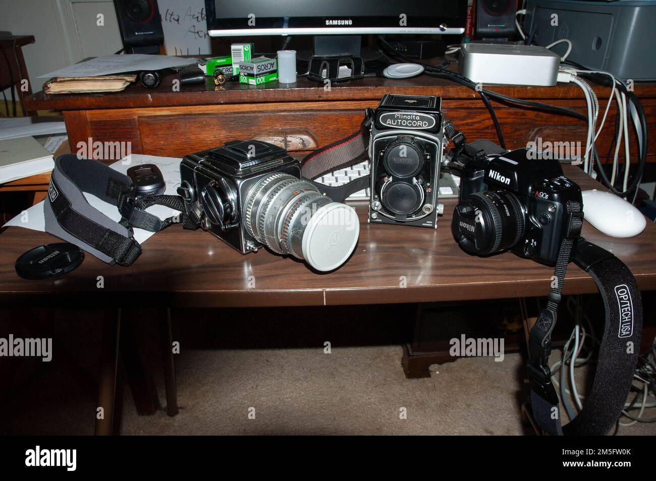 Due fotocamere di medio formato (Hasselblad e Minolta Autocord) e una fotocamera Nikon 35mm su una scrivania con attrezzatura per computer. Foto Stock