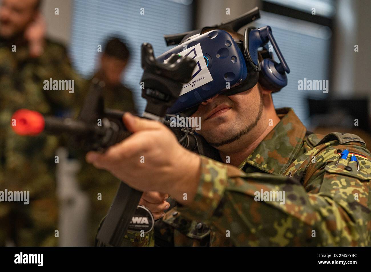 Un aereo tedesco dell'aeronautica spara una carabina M4A1 durante una simulazione alla base aerea di Ramstein, Germania, 16 marzo 2022. Il sistema di realtà virtuale Street Smarts è un'esperienza immersiva e completa con feedback in tempo reale, in modo che le unità possano prepararsi alle situazioni ad alto rischio e agli scenari peggiori in modo sicuro, conveniente e coerente. Foto Stock