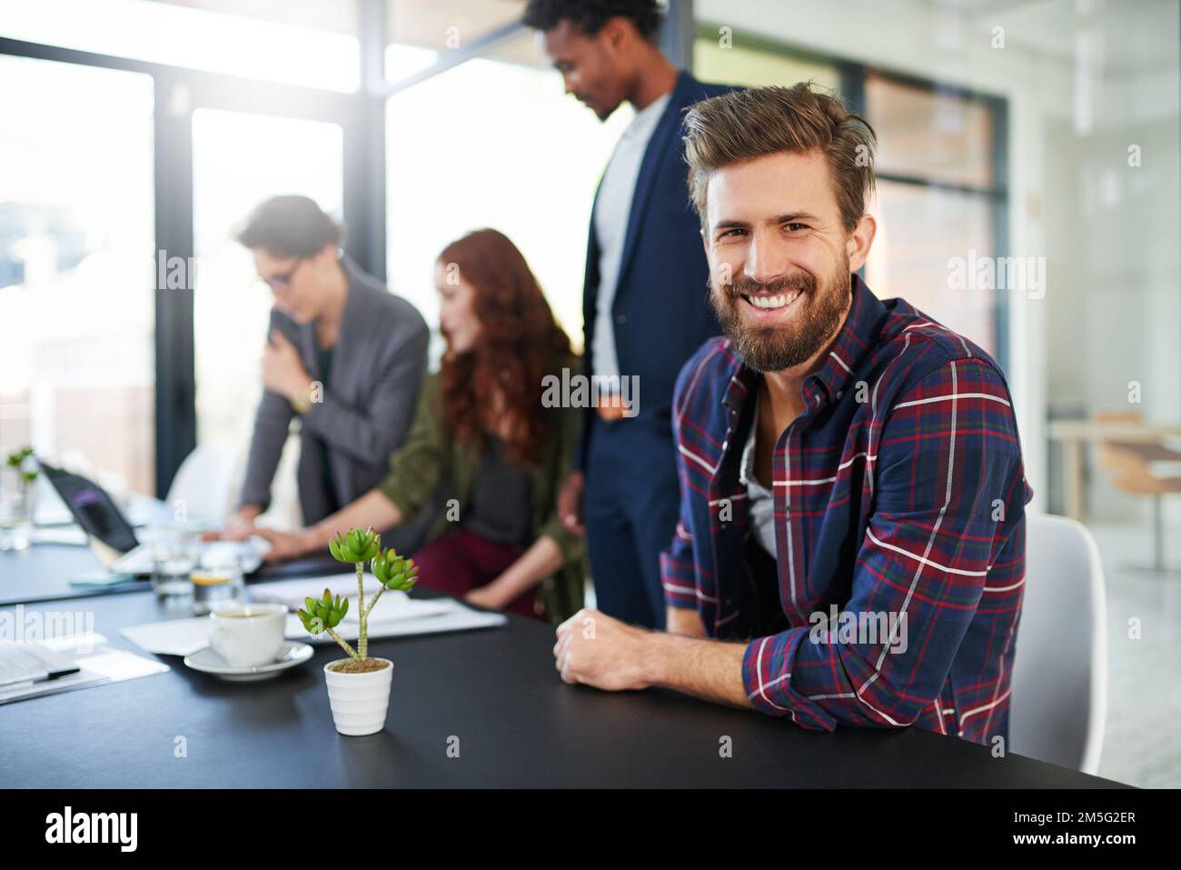Im non vedo l'ora di raggiungere il successo con il mio team. Ritratto di un giovane creativo seduto in un incontro con i suoi colleghi. Foto Stock