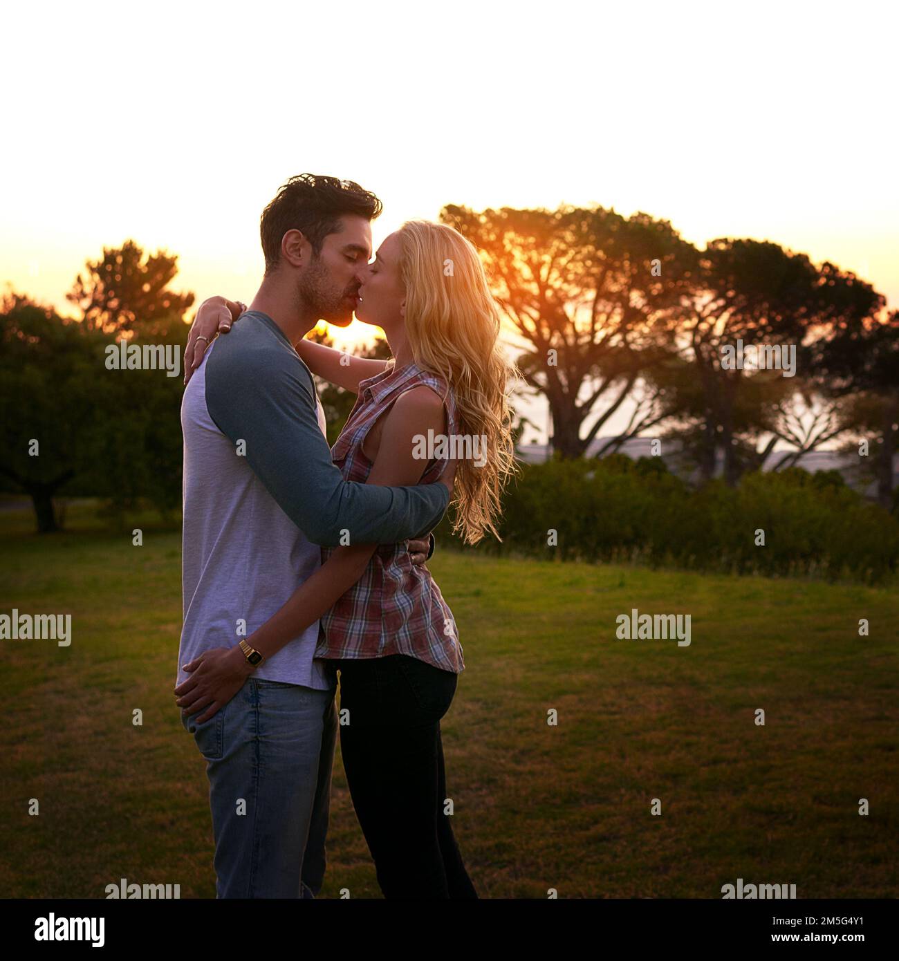 Cant ottenere abbastanza dei vostri baci. una giovane coppia affettuosa che condivide un bacio al tramonto. Foto Stock