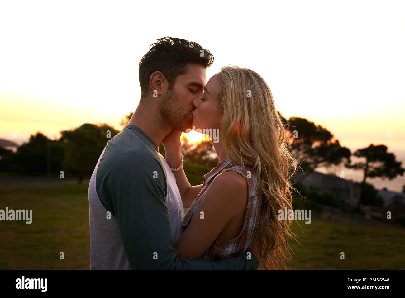 Testa sopra guarisce nell'amore. una giovane coppia affettuosa che condivide un bacio al tramonto. Foto Stock