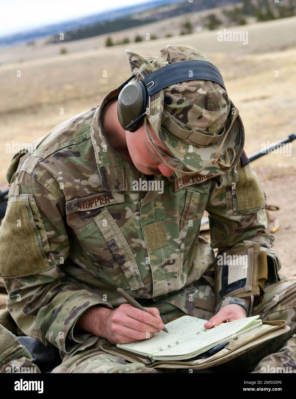 Un Airman che partecipa al corso Nuclear Advanced Designated Marksman scrive delle note nel suo libro di dati del 16 marzo 2022 a Camp Guernsey, Wyoming. Il data book viene utilizzato per tenere traccia dei propri scatti e li aiuta a migliorare ogni scatto. Foto Stock