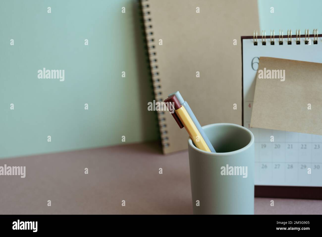 Supporto per notebook e matita, calendario, blocco note sulla scrivania. sfondo parete menta. spazio di lavoro, piano di nuovo anno, attività, forniture per ufficio Foto Stock