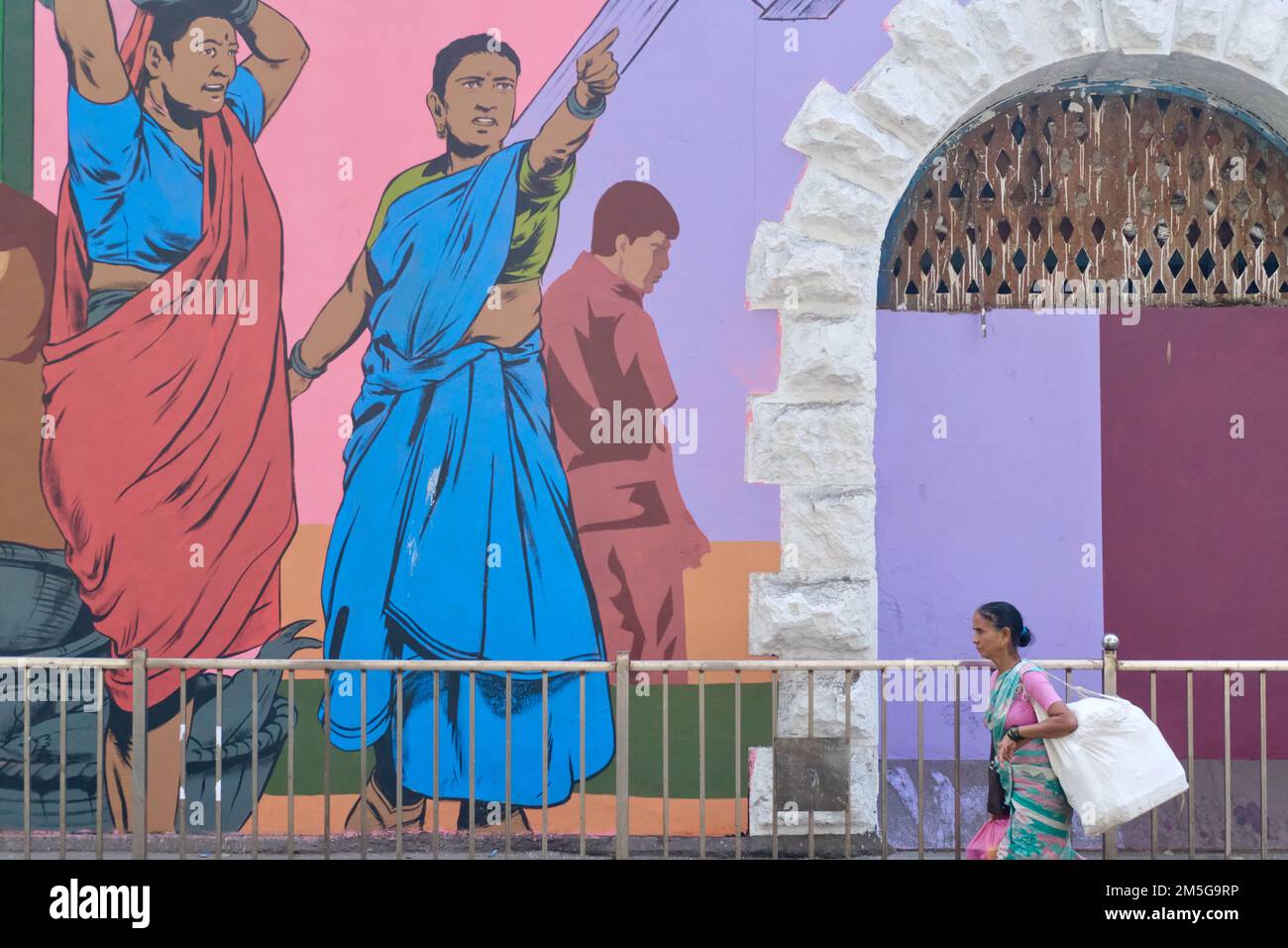 Una donna passa un dipinto a parete colorato a Sassoon Docks, Colaba, Mumbai, India Foto Stock