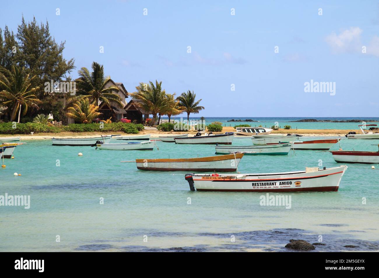 Barche colorate in una baia di sabbia tropicale con palme sull'Oceano Indiano, Mauritius Foto Stock