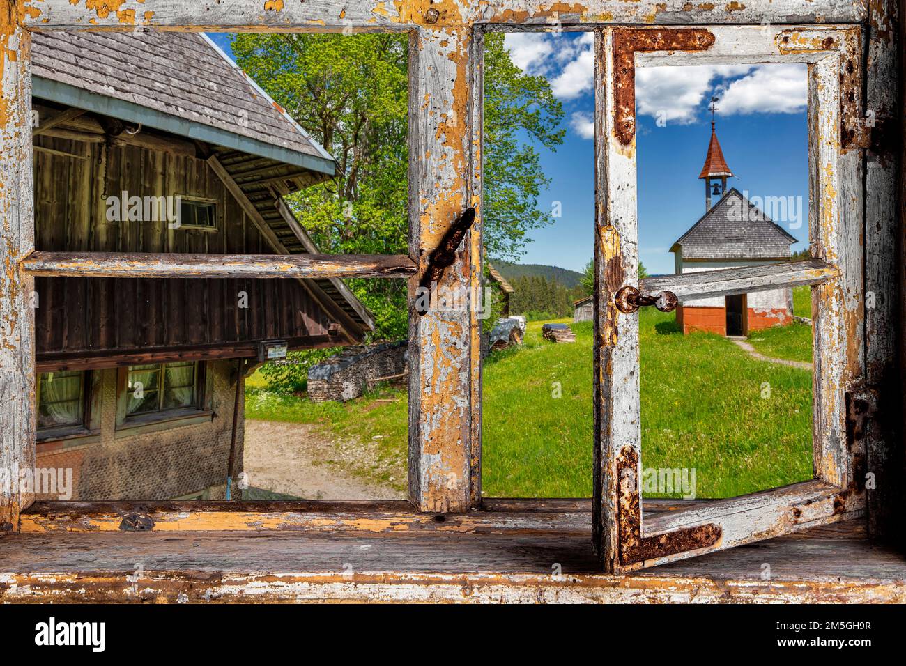 Vista da una finestra di legno su una fattoria con una cappella Foto Stock