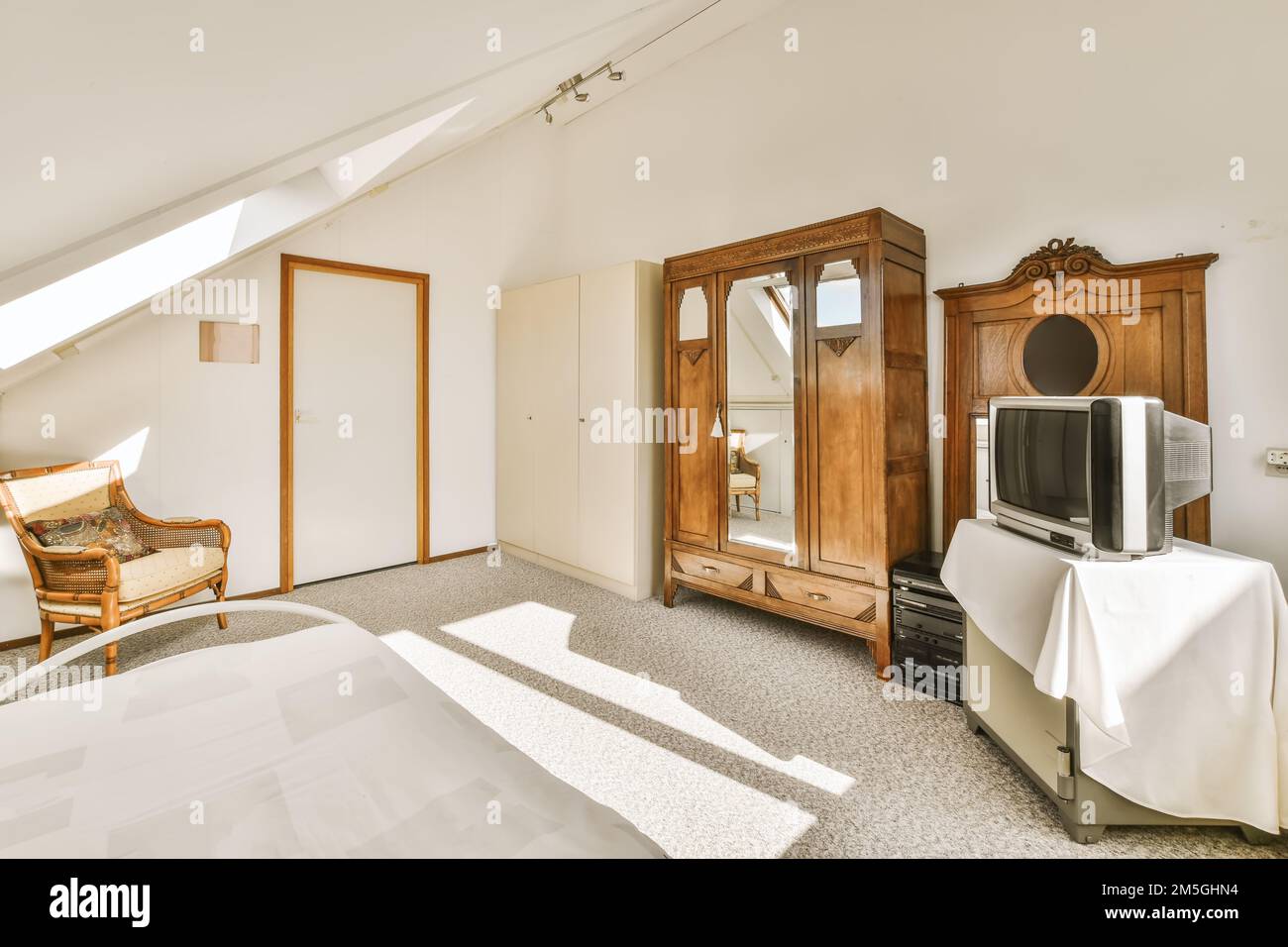 una camera da letto con un letto, comò e televisione nell'angolo della stanza sulla sinistra è una finestra Foto Stock