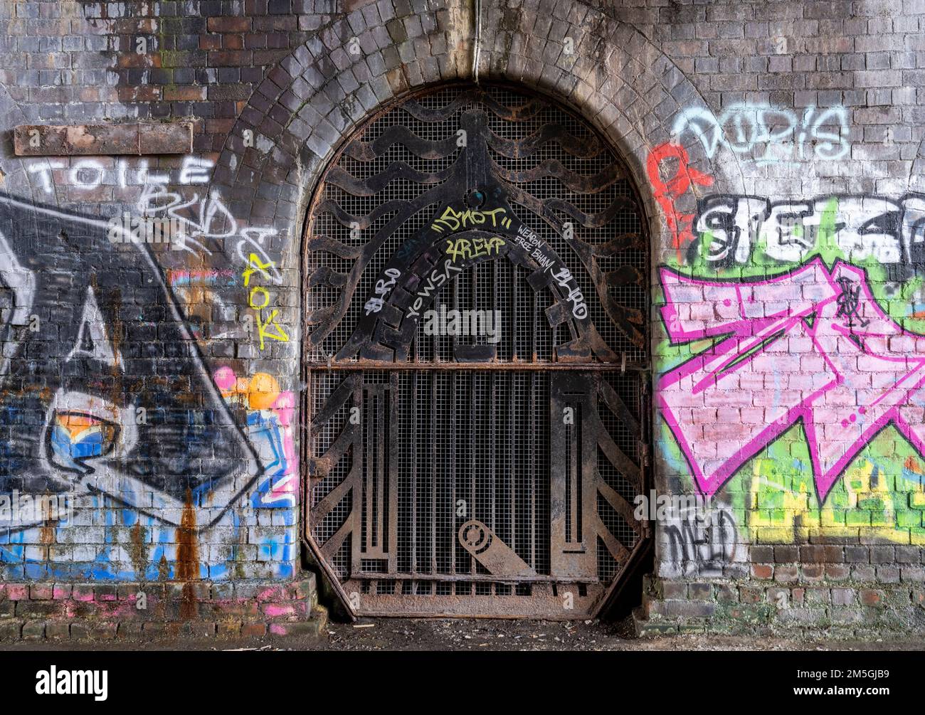 Grigliare sul tunnel sotto un ponte sul canale di Birmingham con grafitti Foto Stock