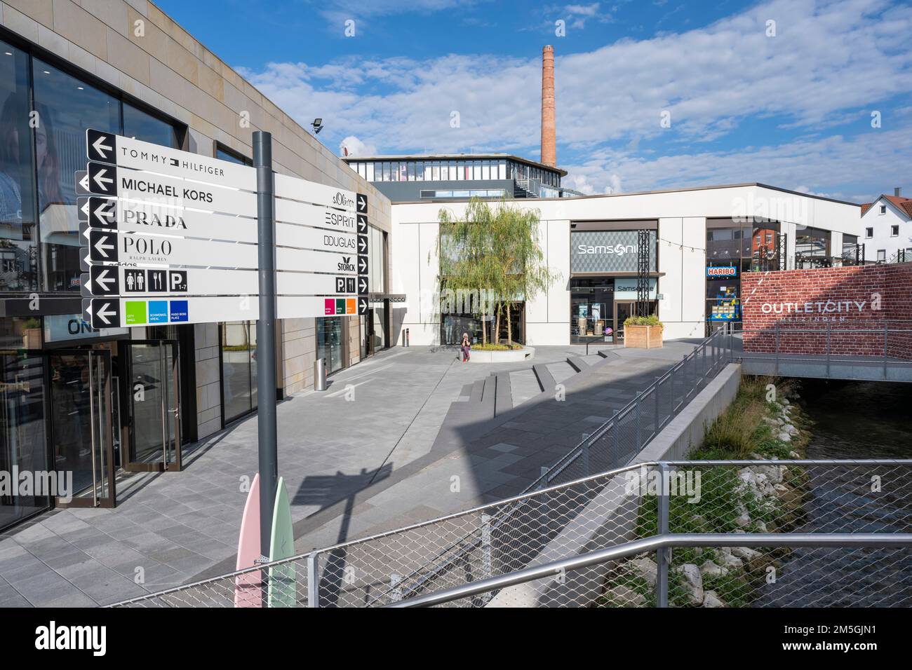Piazza, punto d'incontro nell'area esterna con segnaletica da Outletcity Metzingen, quartiere di Reutlingen, Baden-Wuerttemberg, Germania Foto Stock