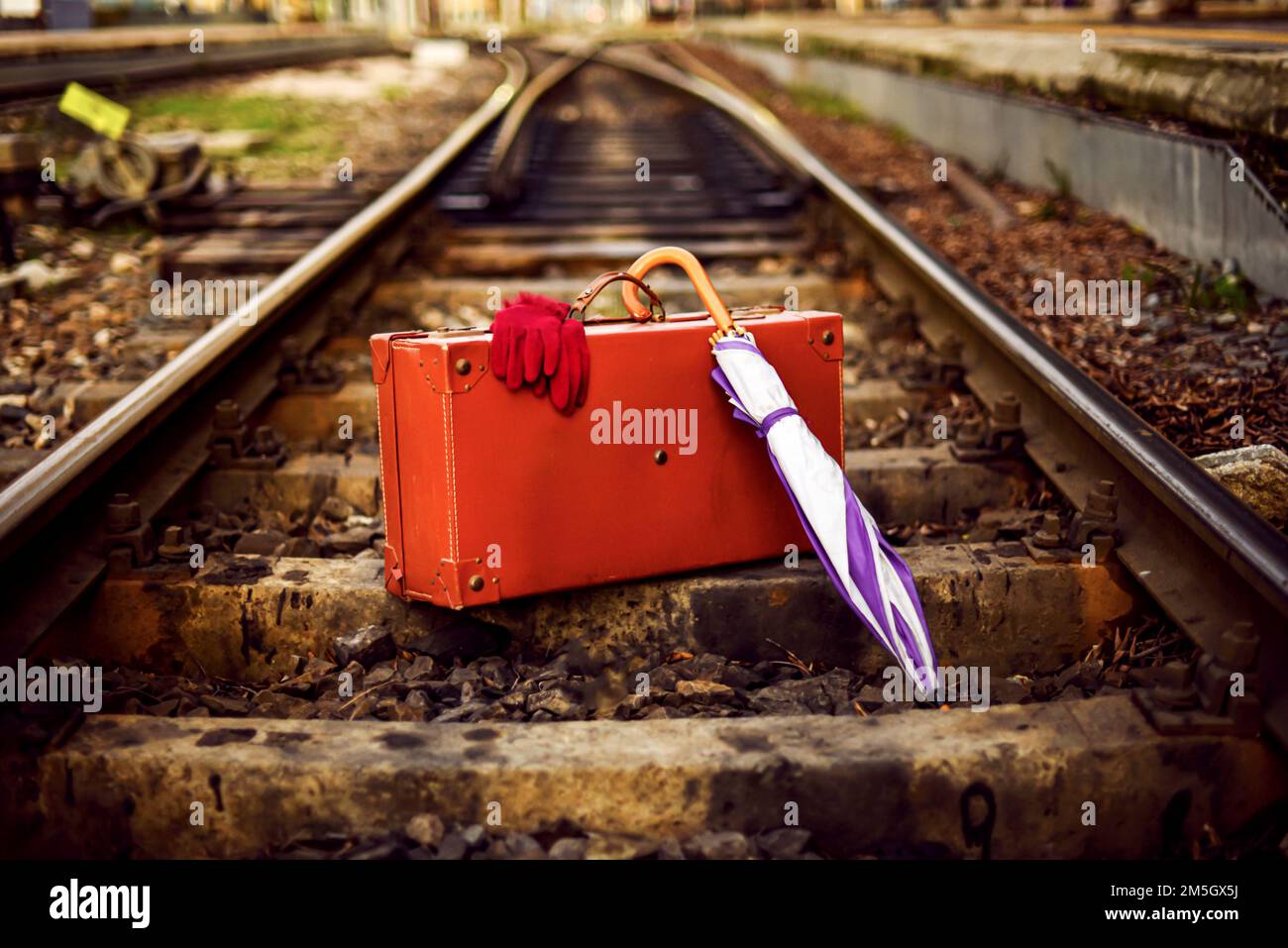 Concetto di vita morta di una fotografia di vacanza in una stazione ferroviaria, primo piano. Una vecchia valigia in pelle e un paio di guanti. Foto Stock