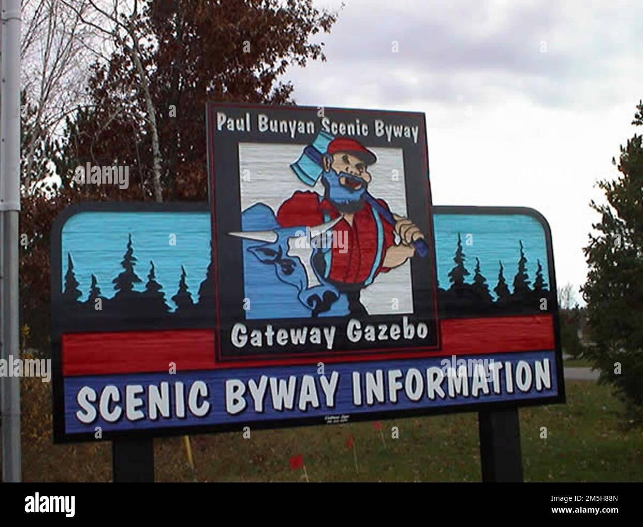 Paul Bunyan Scenic Byway - Gazebo Gateway cartello di benvenuto. Un segno raffigurante la leggenda Paul Bunyan e il suo bue 'Babe' tra pini, dipinti in blu e rossi vividi, accoglie i visitatori della Paul Bunyan Scenic Byway. Location: Italy (46,603° N 94,308° W) Foto Stock