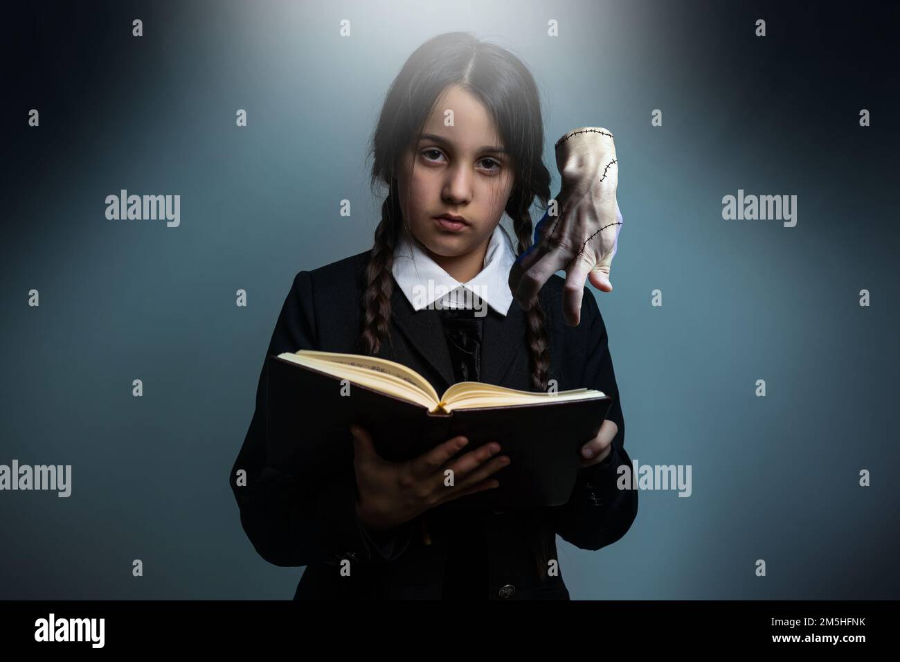 Ritratto di bambina con costume di mercoledì Addams durante Halloween. Espressione  seria e atmosfera scura con sfondo scuro Foto stock - Alamy