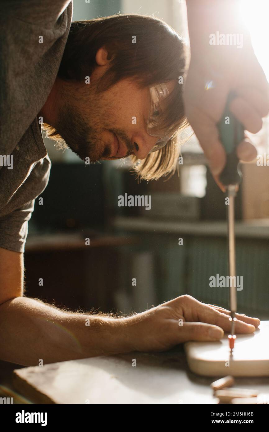 Avvitare le spine in un pannello di legno. Produzione di mobili per bambini e giochi educativi. Foto Stock