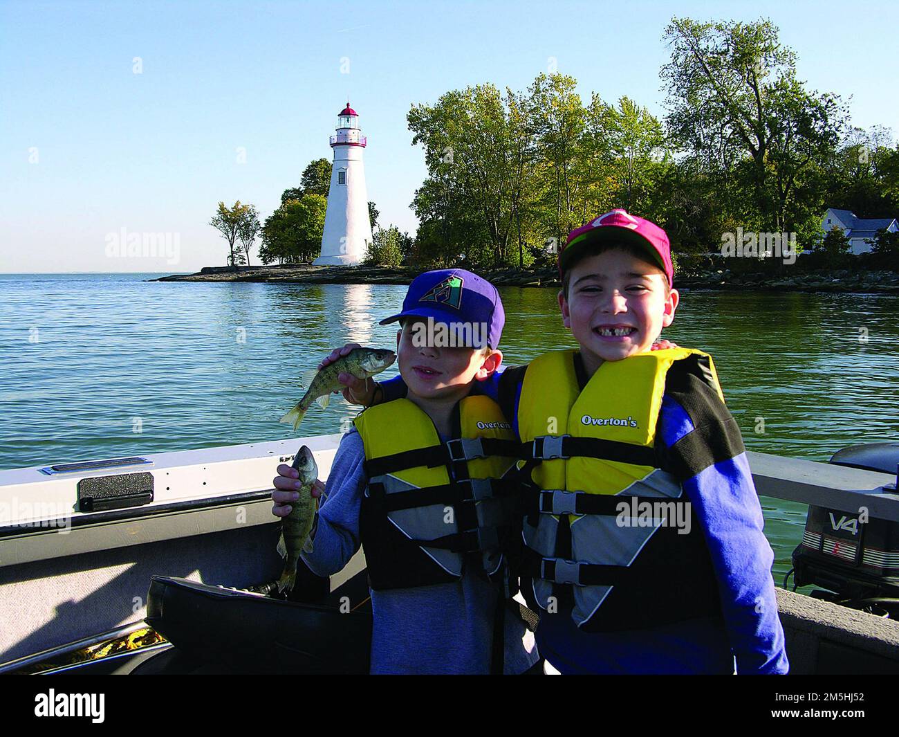Sentiero costiero dell'Ohio sul lago Erie - divertimento sul lago Erie. Un pesce nella mano vale uno nel ... orecchio? Due ragazzi tengono il pescato della giornata sul molo vicino al faro di Marblehead. Il lago Erie offre divertimento a tutte le età per tentare la fortuna alla pesca di persico giallo, walleye e persico. Marblehead Lighthouse, Ohio (41,536° N 82,711° W) Foto Stock