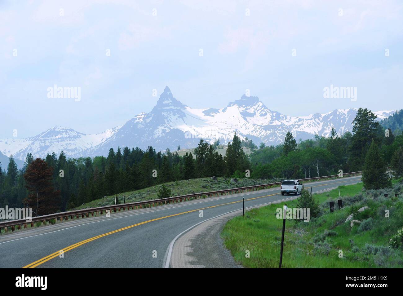 Beartooth Highway - Scenic Pilot e Index Peaks. La lussureggiante erba verde fienga la strada, mentre la neve copre le vette pilota e indice. Posizione: Scenic Pilot and Index Peaks, Wyoming (44,958° N 109,813° W) Foto Stock