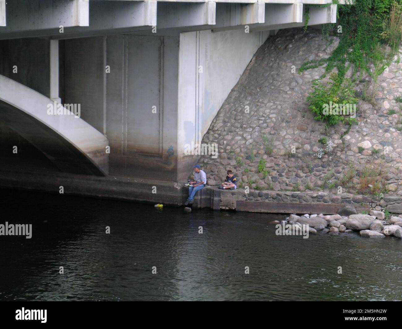 Bordo della natura selvaggia - viaggio di pesca del padre e del figlio. Un padre e un figlio pescano vicino a un ponte sul Mississippi. Location: Italy (47,748° N 93,652° W) Foto Stock