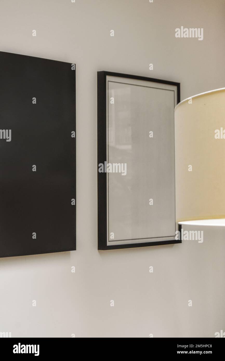 un dipinto bianco e nero è appeso alla parete accanto ad una lampada in una stanza con due opere d'arte incorniciate Foto Stock