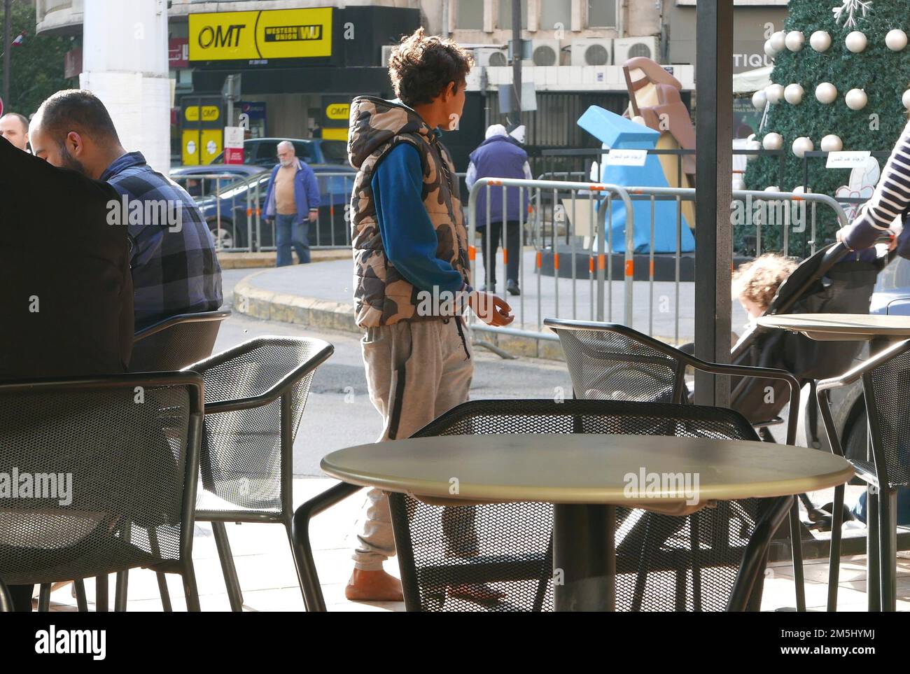 Beirut, Libano. 27th Dec, 2022. Un ragazzo siriano mendicante a piedi nudi in una caffetteria a Beirut, Libano, dicembre 27 2022. Nonostante l’ACNUR, l’Agenzia delle Nazioni Unite per i rifugiati e molte altre ONG forniscano aiuto ai rifugiati siriani in Libano, molti bambini sono sfruttati dal traffico. (Foto di Elisa Gestri/SIPA USA) Credit: Sipa USA/Alamy Live News Foto Stock