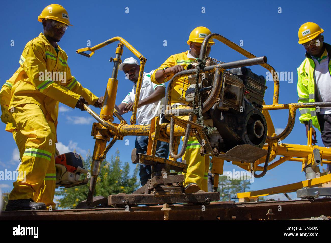 Lavoratori che utilizzano una chiave meccanica per imbullonare un binario ferroviario, costruendo infrastrutture di trasporto nei paesi in via di sviluppo Foto Stock