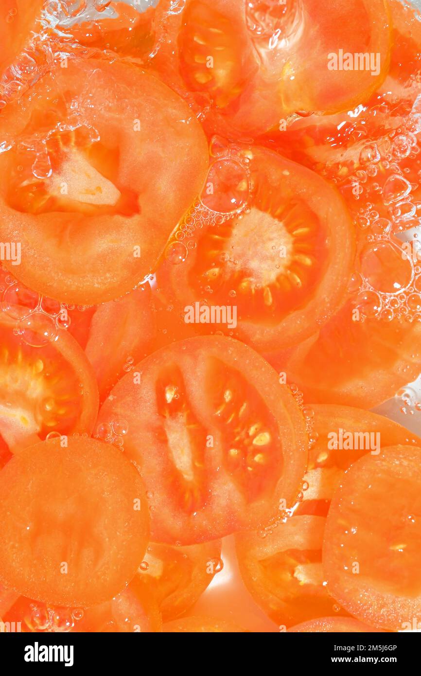 Primo piano fette fresche di pomodoro su sfondo bianco. Fette di pomodoro in acqua frizzante su fondo bianco, primo piano. Immagine verticale. Foto Stock